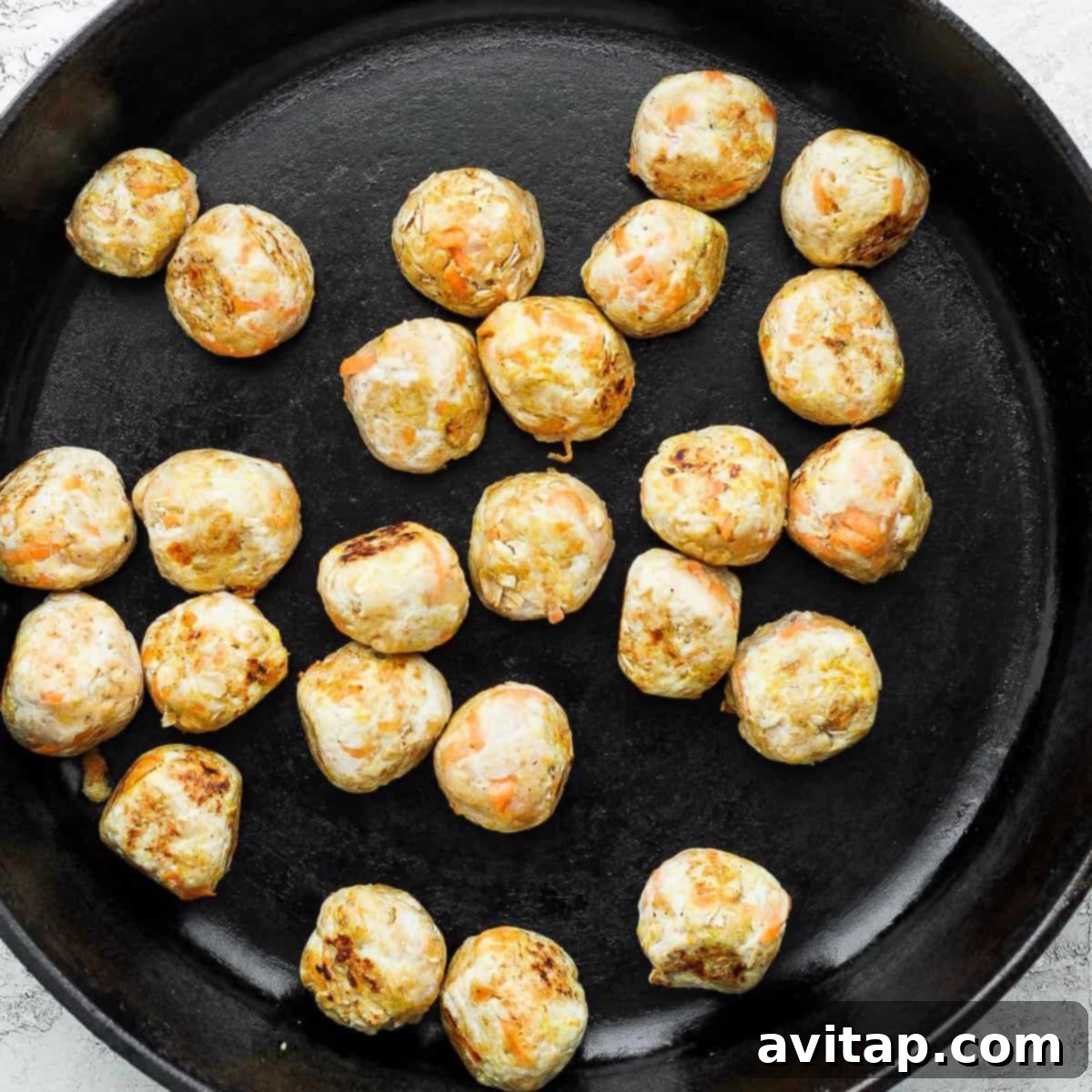 Vibrant Green Curry Chicken Meatballs 4 Golden-brown chicken meatballs sizzling in a cast iron pan, perfectly seared and ready to be simmered in the rich green curry sauce.