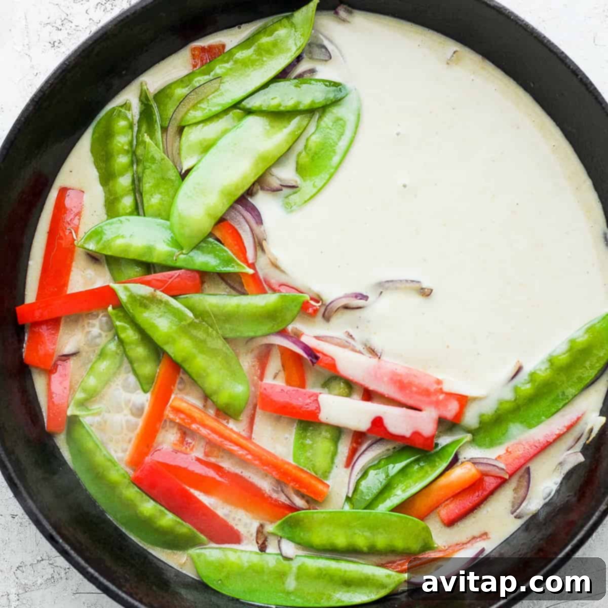 Vibrant Green Curry Chicken Meatballs 5 Vibrant green curry sauce with tender vegetables simmering in a cast iron pan, forming the delicious and aromatic base for the chicken meatballs.
