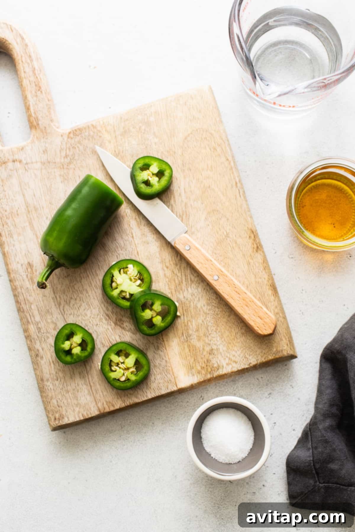 Freshly sliced jalapeños on a wooden cutting board, ready for cocktail infusion.