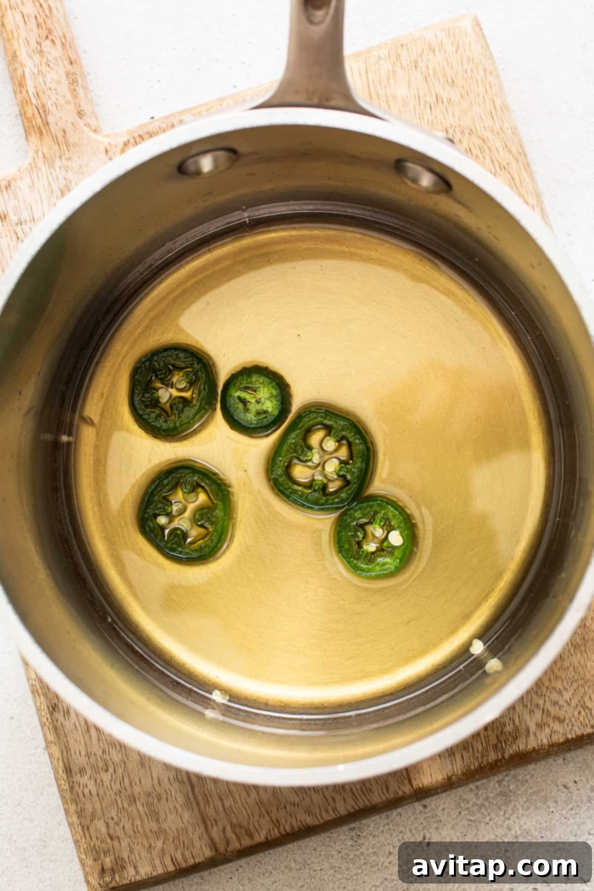 Spicy simple syrup simmering gently in a small saucepan on a stovetop.