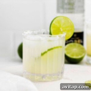 A classic margarita in a glass with a salted rim, on a countertop.
