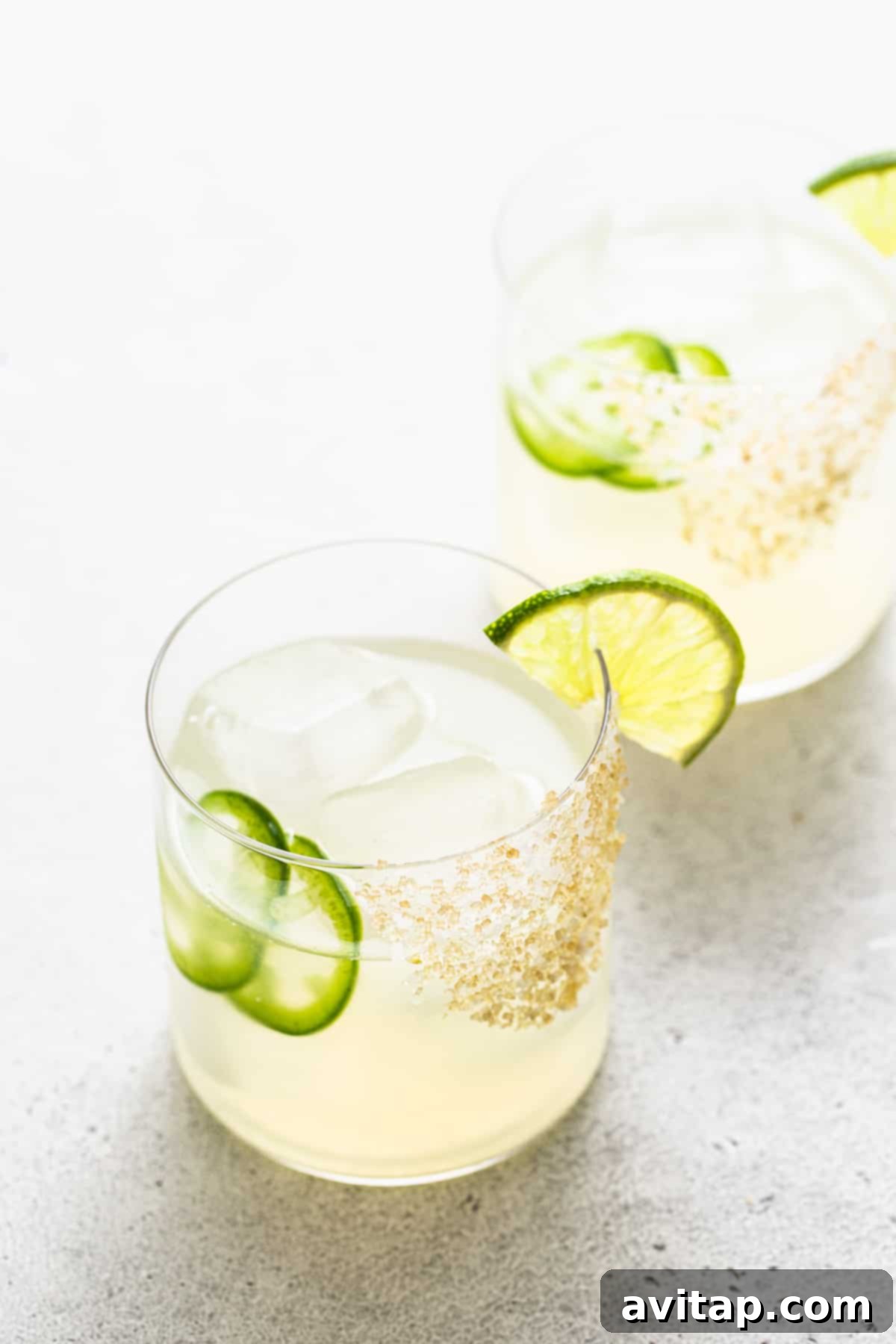 A vibrant spicy mezcal margarita in a salt-rimmed glass, garnished with lime and jalapeño.