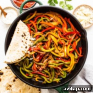 A skillet filled with colorful fajita peppers and onions, served alongside warm tortillas.