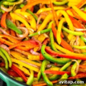 A vibrant green skillet on a stovetop, capturing the cooking process of colorful bell peppers and onions.