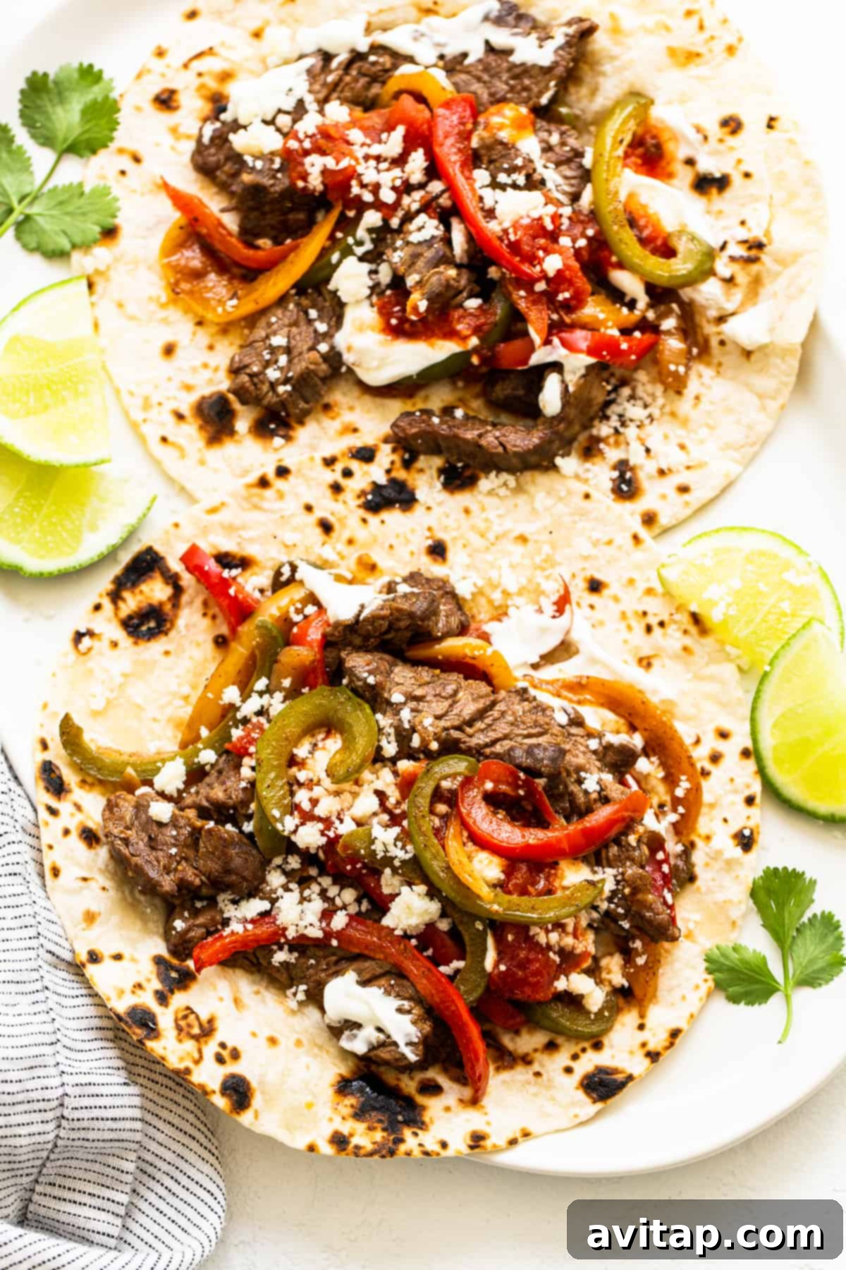 Sizzling steak fajitas on a warm tortilla, garnished with fresh cilantro and lime.