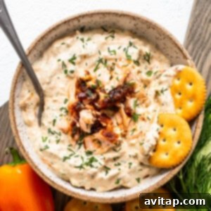 Smoked salmon dip in a bowl with a side of crackers and fresh dill for garnish.