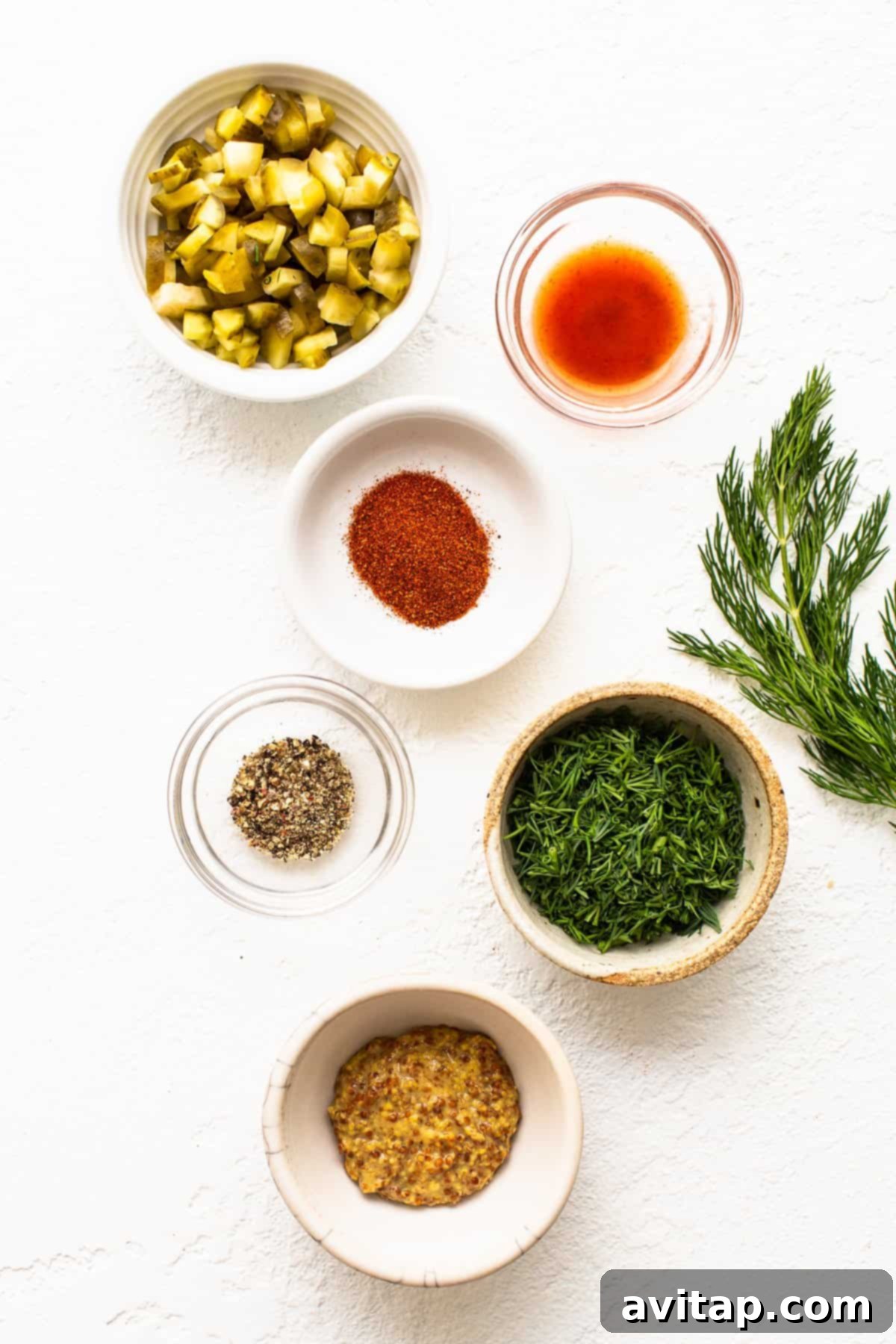 A vibrant selection of fresh ingredients laid out, including a block of cream cheese, Greek yogurt, fresh dill, lemon, and a container of smoked salmon.