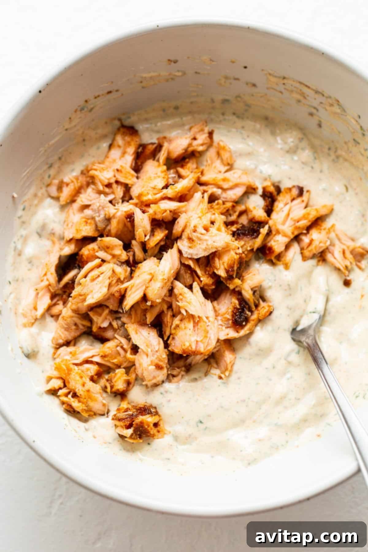 Flaked smoked salmon gently mixed into the creamy dill and pickle-infused base, showing the delicious texture.