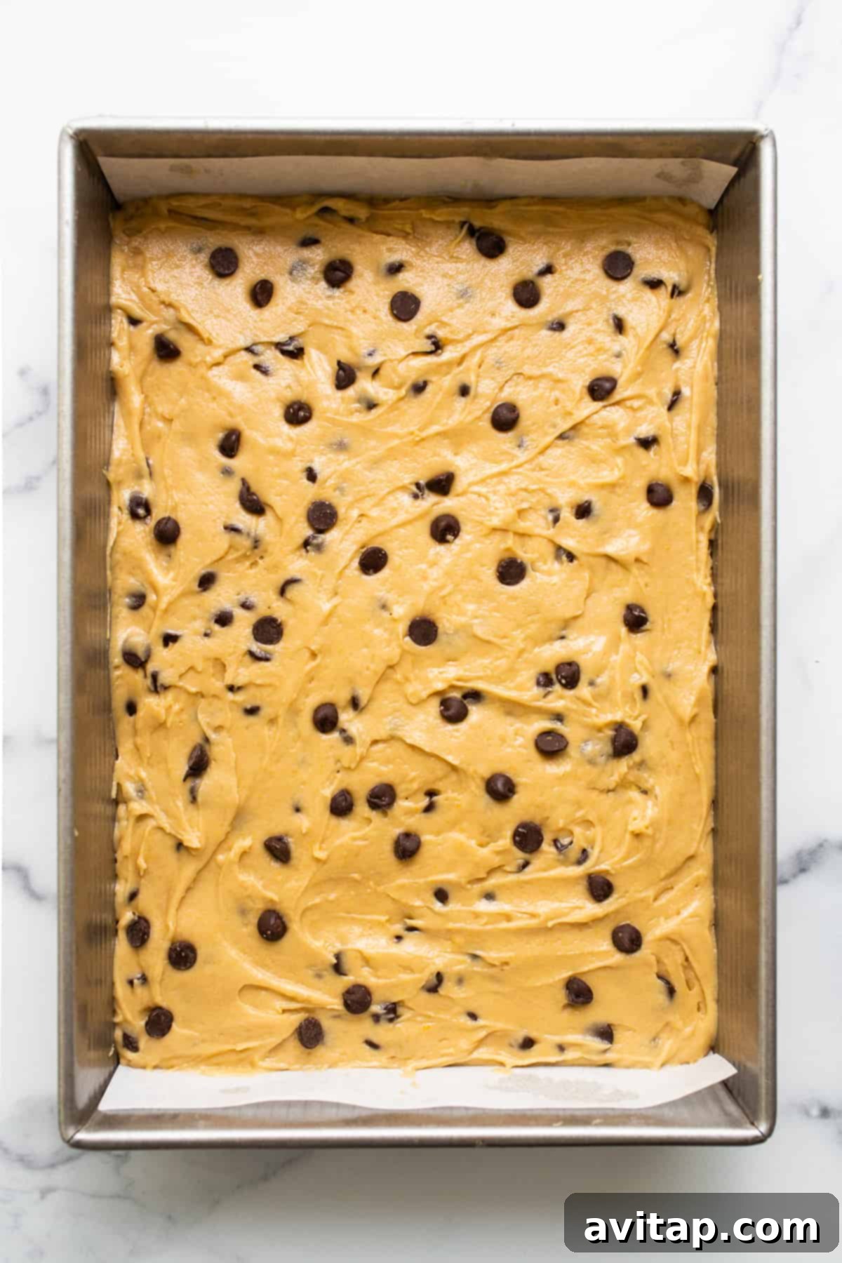 Maple-Infused Chocolate Chip Blondie Bars 6 Beautifully golden-brown maple chocolate chip cookie blondies, freshly baked and still warm in the baking dish, showing their chewy texture.