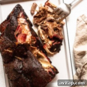 Tender Smoked Pork Shoulder 12 Finished pork shoulder resting on a tray, showcasing its tender texture and delicious bark after coming off the smoker.