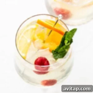 White Wine Spritzer in a wine glass, garnished with fresh fruit.