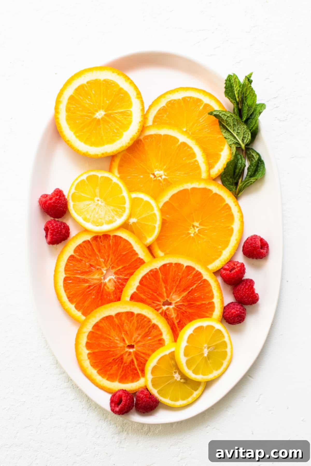 Assortment of fresh fruits and herbs including lemon, lime, berries, and mint, perfect for garnishing white wine spritzers.