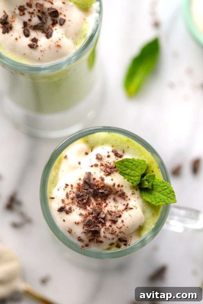 Close-up of a Healthy Shamrock Shake in a glass, topped with an extra sprinkle of dark chocolate chips, highlighting the refreshing mint and rich chocolate combination.