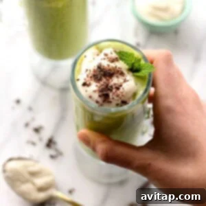 A vibrant green Healthy Shamrock Shake in a glass, topped with chocolate chips.