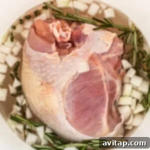 Turkey breast brining in a bucket with fresh herbs and onion.