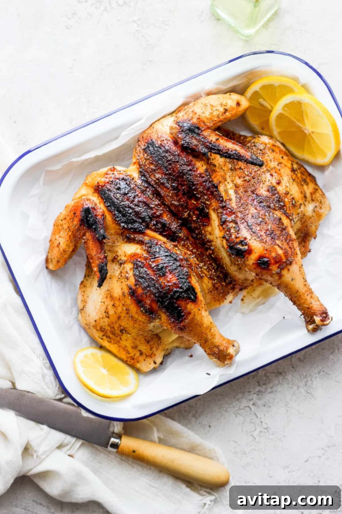 Grill a whole chicken with us by brining, spatchcocking, dry rubbing, and grilling it to juicy perfection! A beautifully spatchcocked chicken, perfectly grilled and resting on a platter, ready to be served.