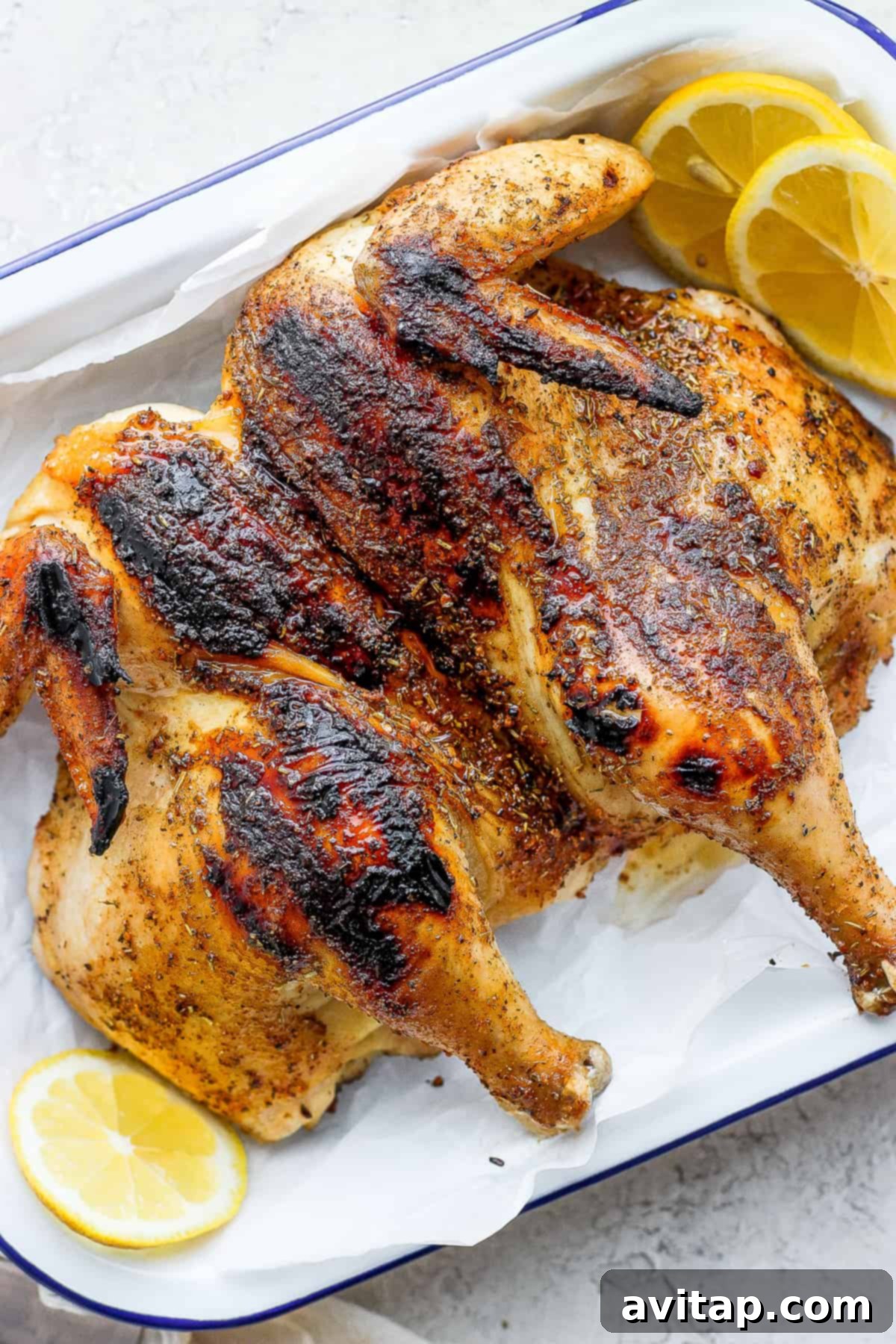 Cooked whole chicken on platter. A perfectly cooked whole spatchcock chicken, golden-brown and glistening, presented on a rustic platter.