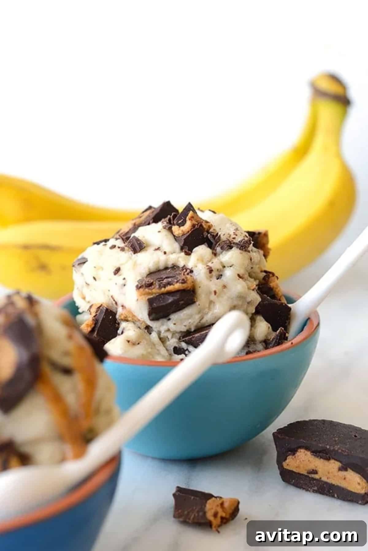 A vibrant, creamy scoop of Peanut Butter Cup Banana Nice Cream, drizzled with peanut butter and topped with mini peanut butter cups, sitting in a bowl.