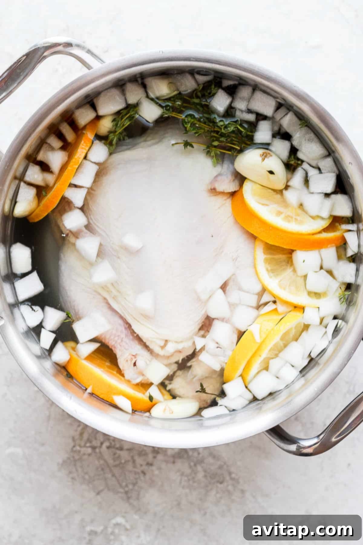 A whole chicken submerged in a flavorful brine inside a large pot, ready for refrigeration.