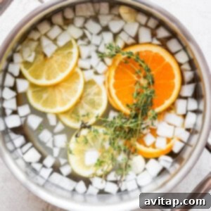 All brine ingredients including garlic, onion, citrus, and herbs in a pot.
