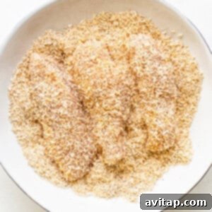 Raw chicken tenders breaded with a coconut and spice mixture, ready for air frying.