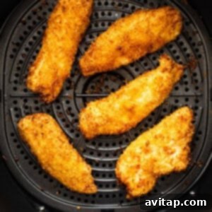 Crispy coconut chicken tenders freshly cooked in an air fryer, glowing golden brown.