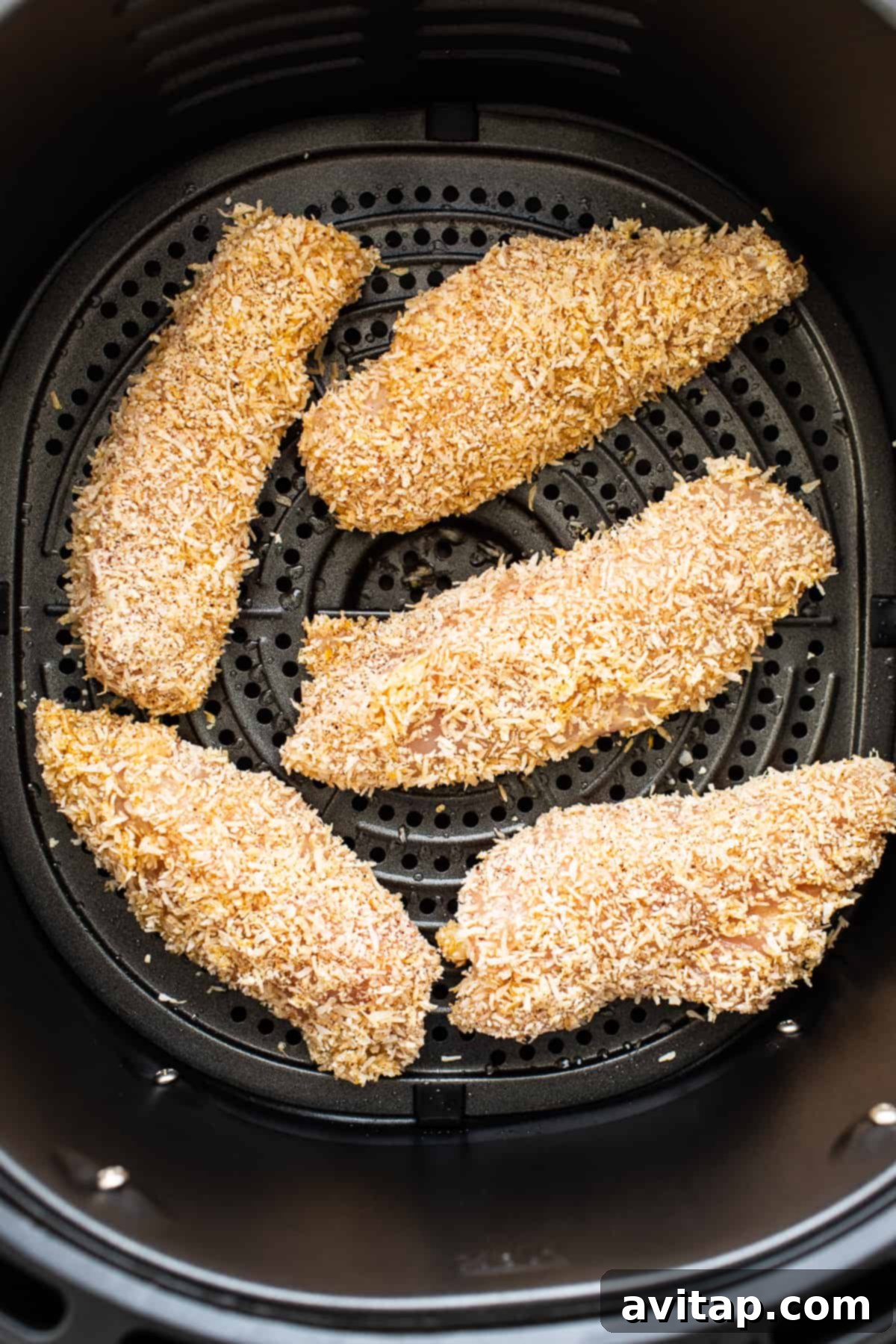 Golden-brown, crispy chicken tenders cooking evenly in an air fryer basket.