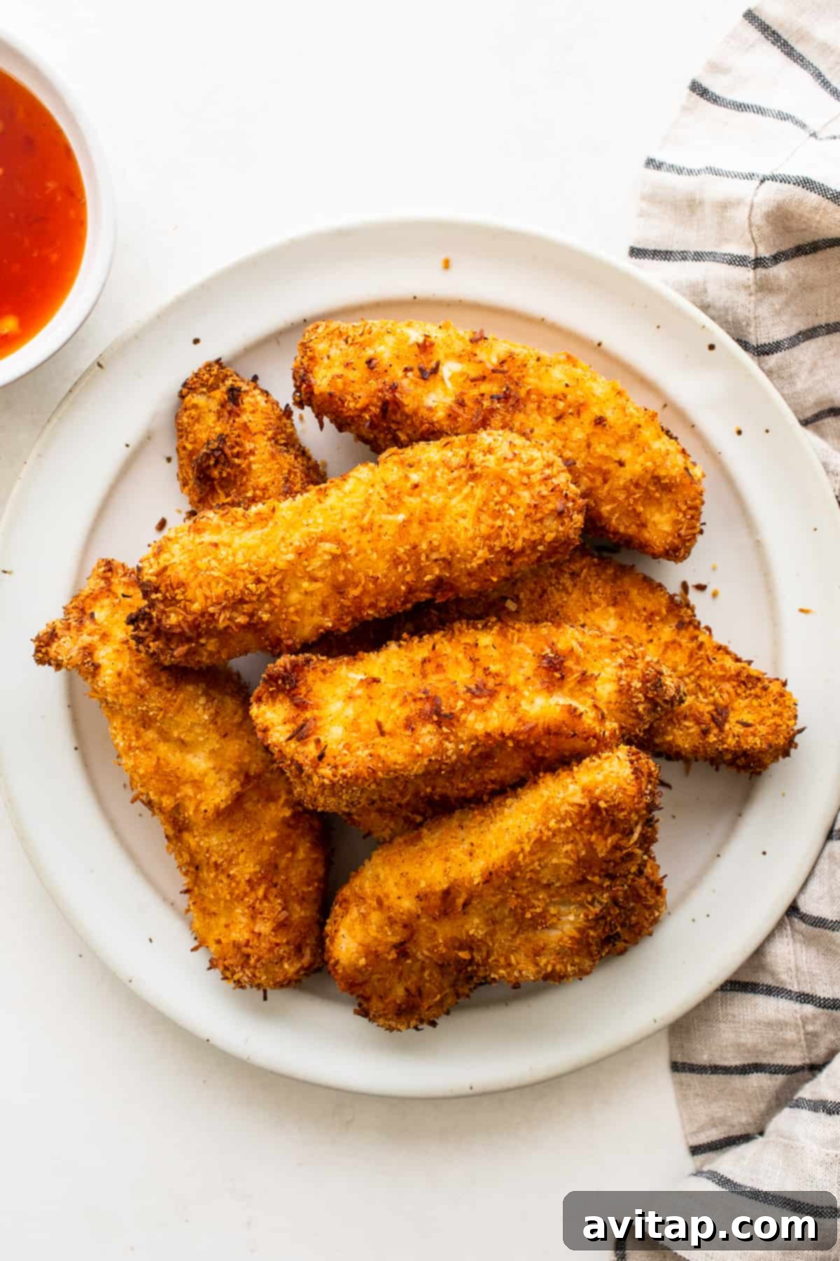 A serving of crispy coconut chicken tenders arranged beautifully on a plate.