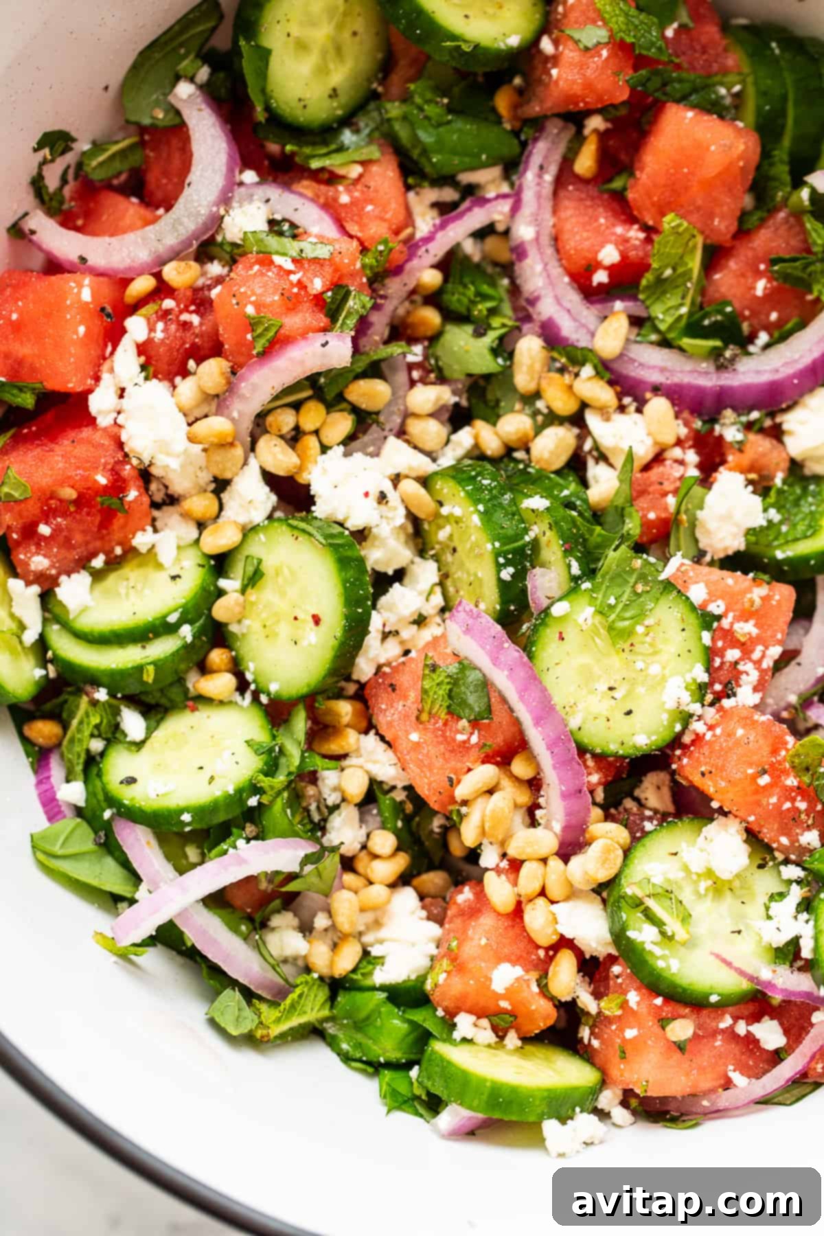 A large bowl of refreshing watermelon salad with feta, cucumber, basil, and mint.