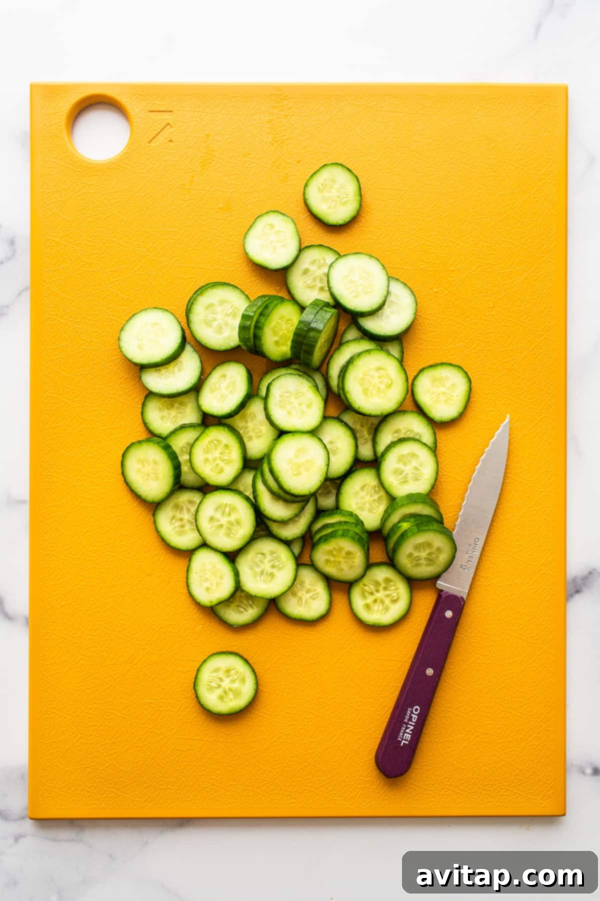 Thinly sliced cucumber on a cutting board, ready for the watermelon salad.