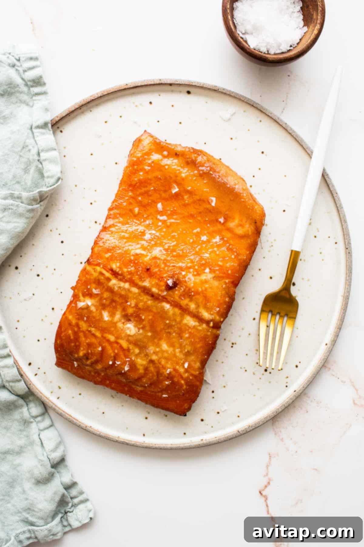 A delectable filet of maple mustard smoked salmon on a white plate, showcasing its beautiful color and texture.