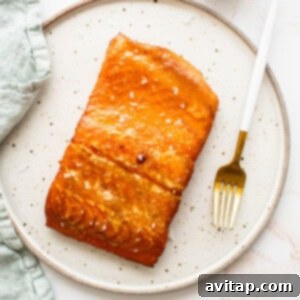 A perfectly smoked maple mustard salmon on a plate, showcasing its golden-brown crust.