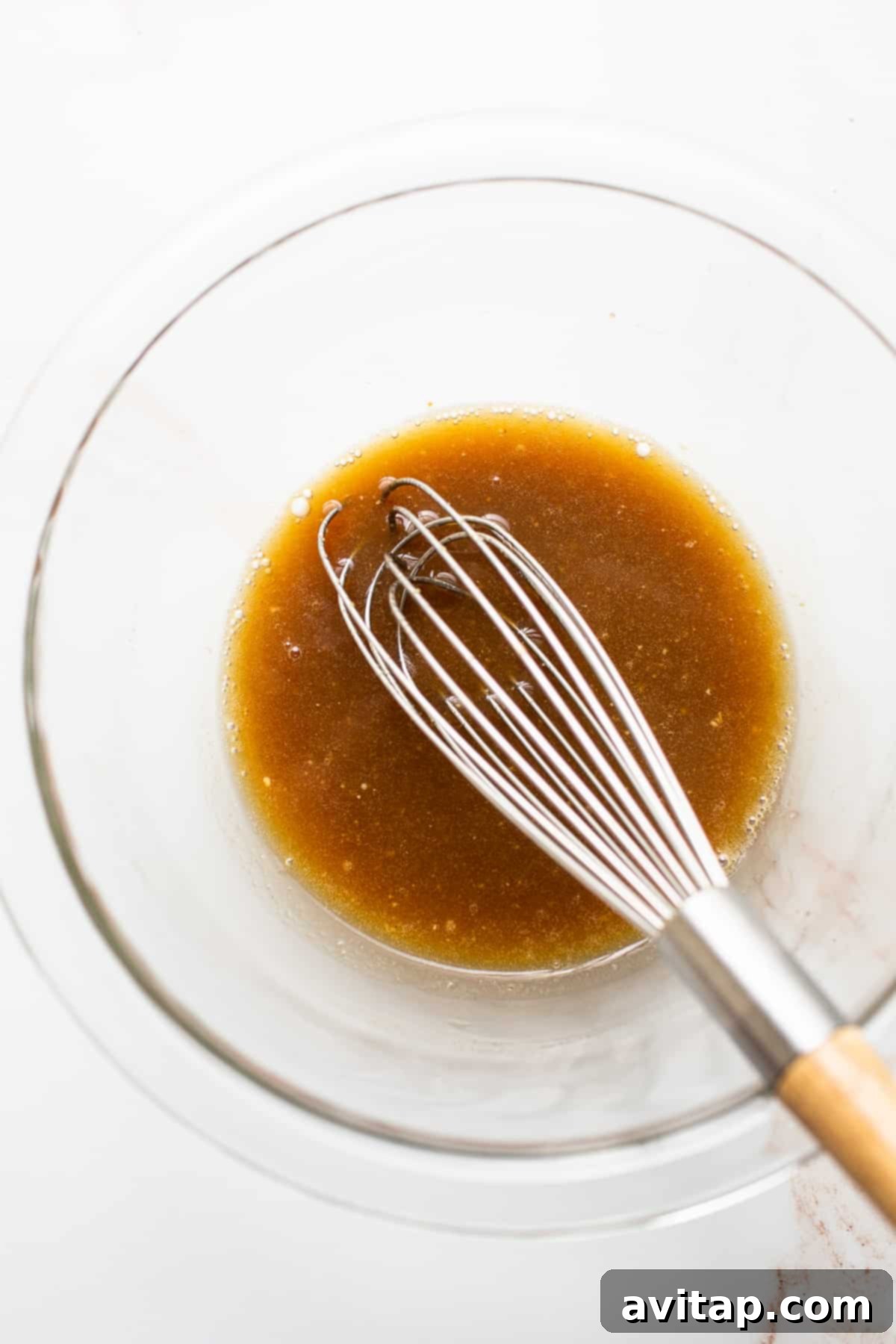 Close-up shot of a salmon filet marinating in a clear bowl, absorbing all the delicious maple mustard flavors.