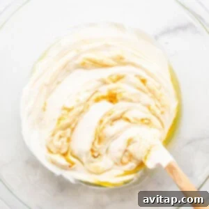 Whipped cream in a bowl with a wooden spoon, showcasing the smooth texture before serving.