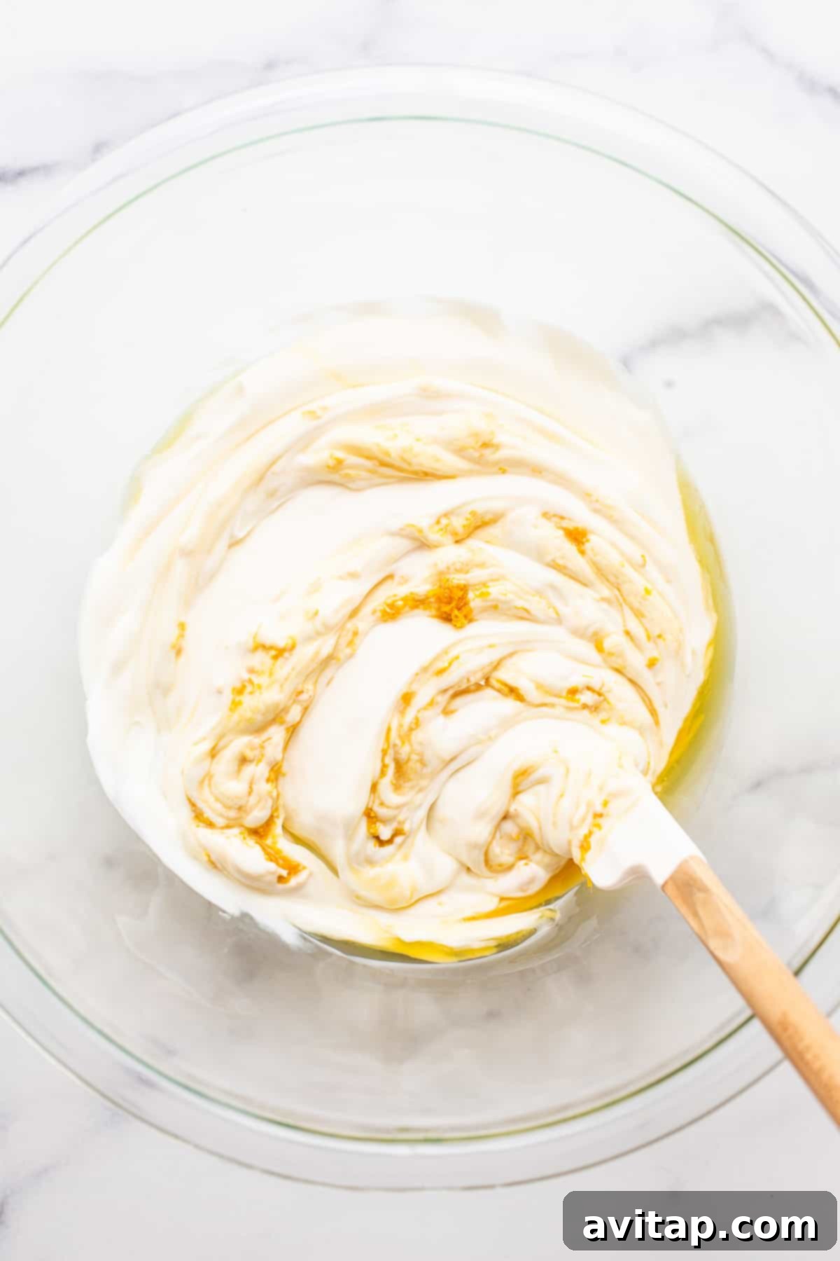 All six essential fruit dip ingredients freshly mixed together in a clear glass bowl, showcasing the creamy, smooth texture and delicate flecks of citrus zest.