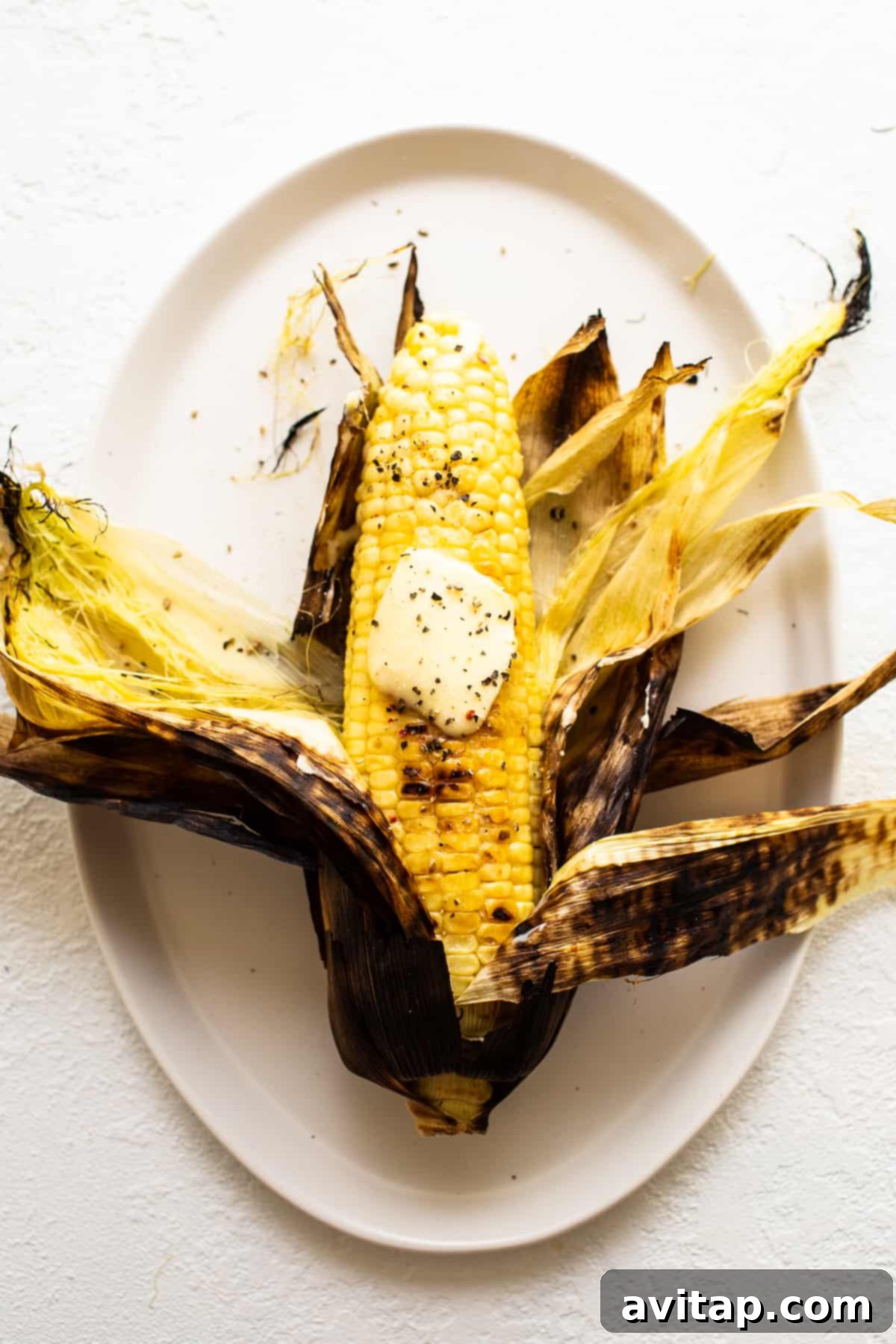Grilled Corn on the Cob: Easy Summer Side with Two Methods Grilled corn on a plate with melted butter, ready to be enjoyed.