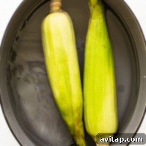 Corn on the cob in a pot, soaking in water.