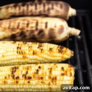 Shucked corn grilling over direct heat.