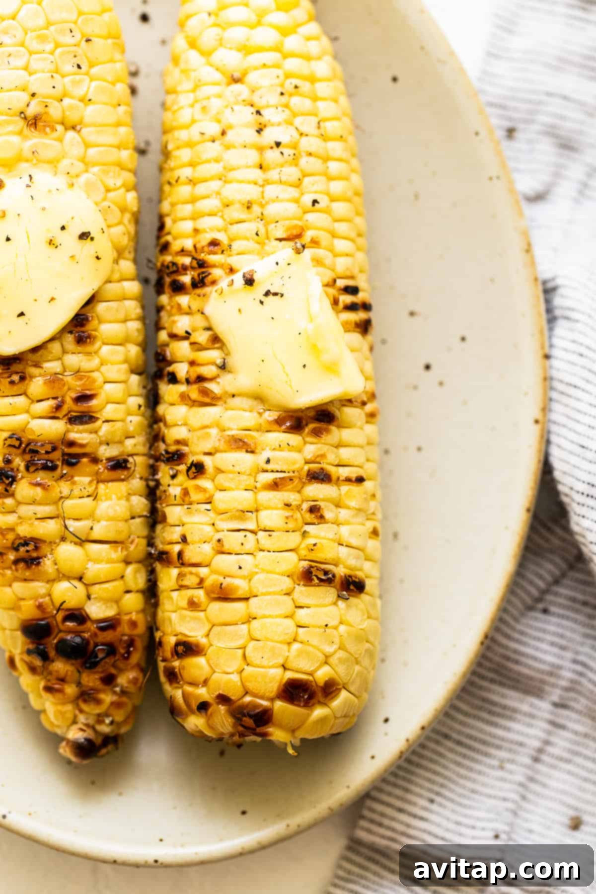 Perfectly Grilled Corn with Butter and Salt Grilled corn on the cob served with a generous pat of butter and a sprinkle of salt.
