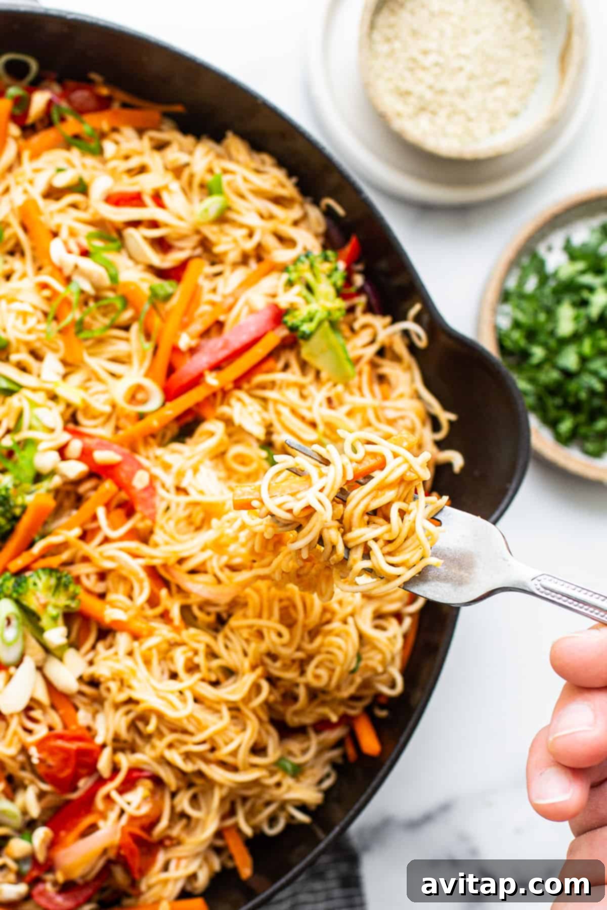 A serving of sesame peanut noodles, garnished with fresh herbs and peanuts, presented in a dish.