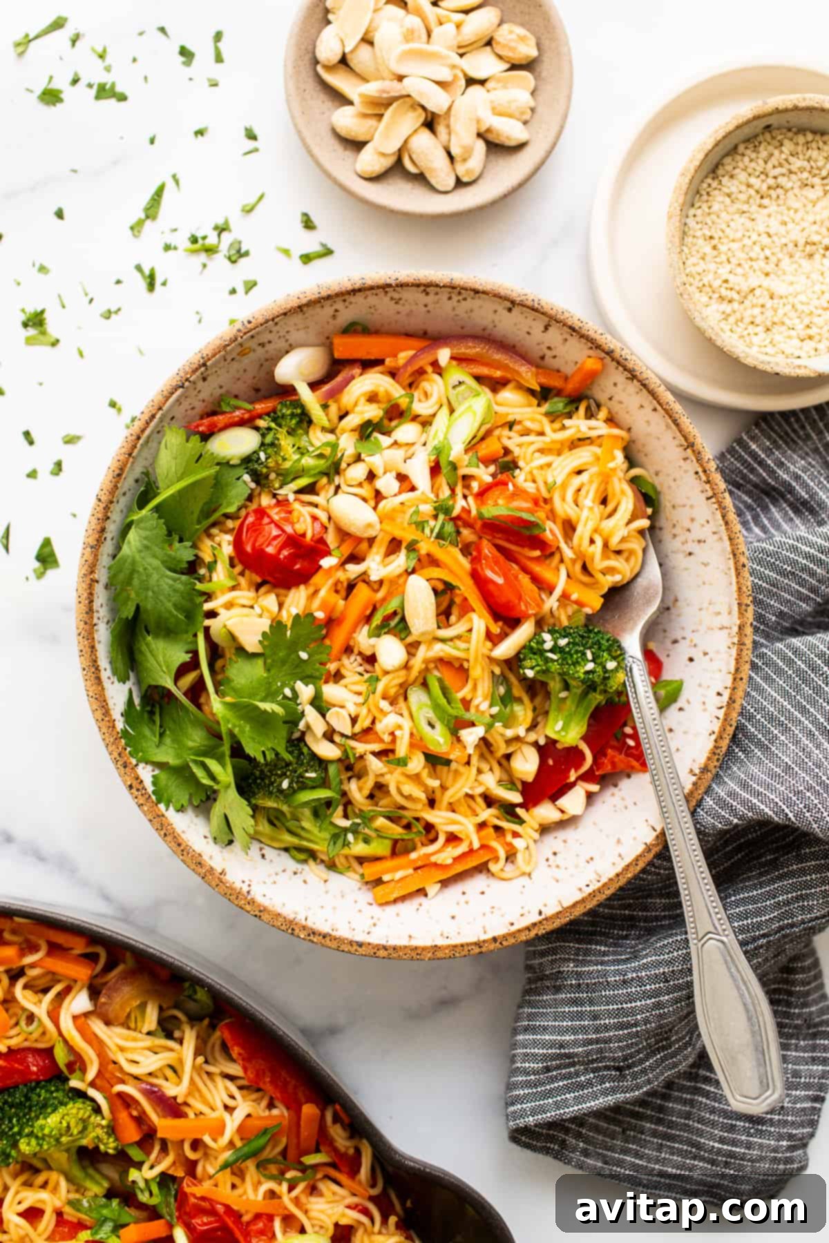 A bowl of peanut butter noodles with a generous mix of vibrant vegetables.