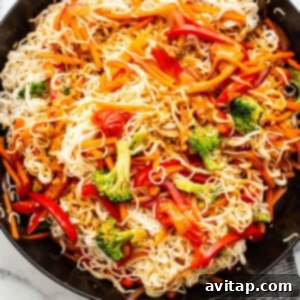 A skillet filled with beautifully coated peanut noodles and vegetables, ready to serve.