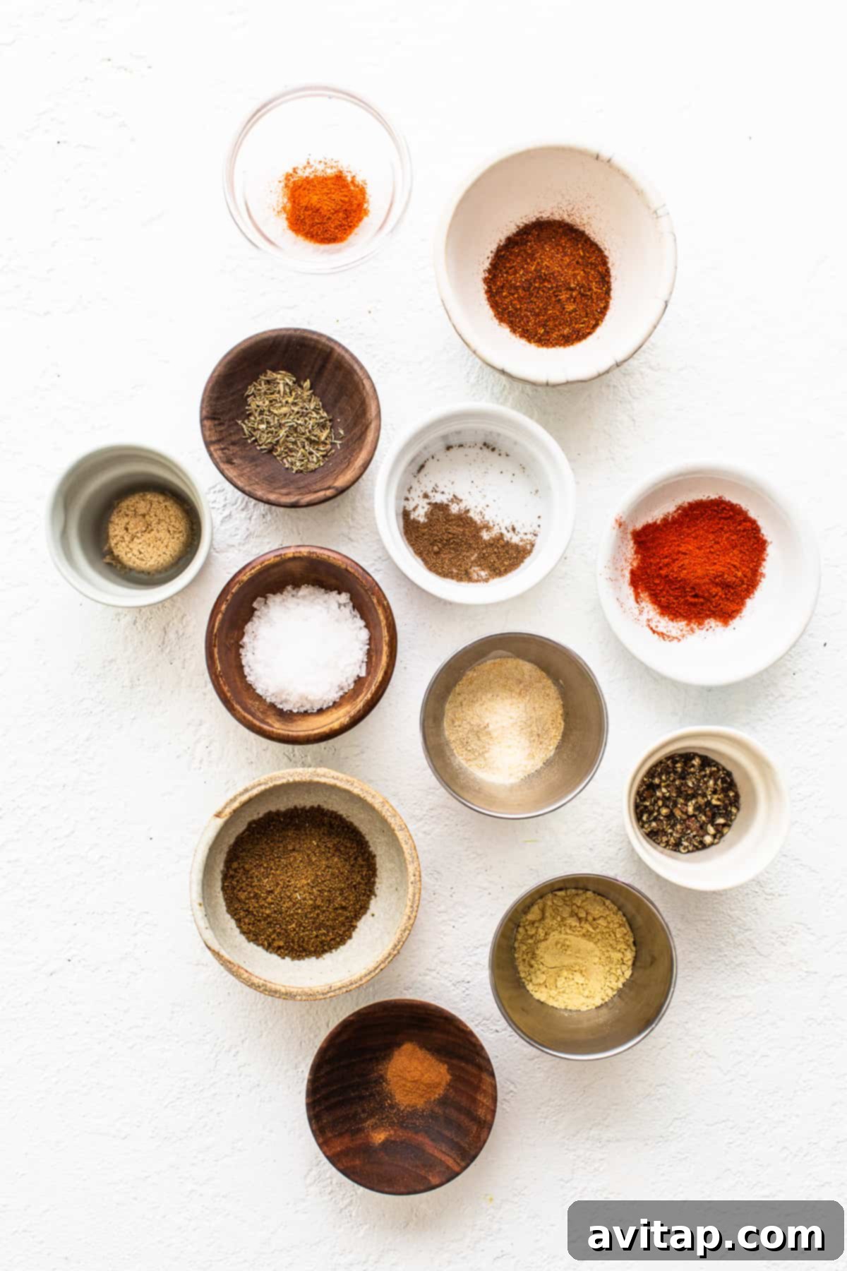 Small bowls containing various individual spices before mixing.