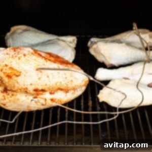 Tender Smoked Turkey Legs 11 Smoked turkey legs cooking on the grates of a smoker, with smoke gently rising.