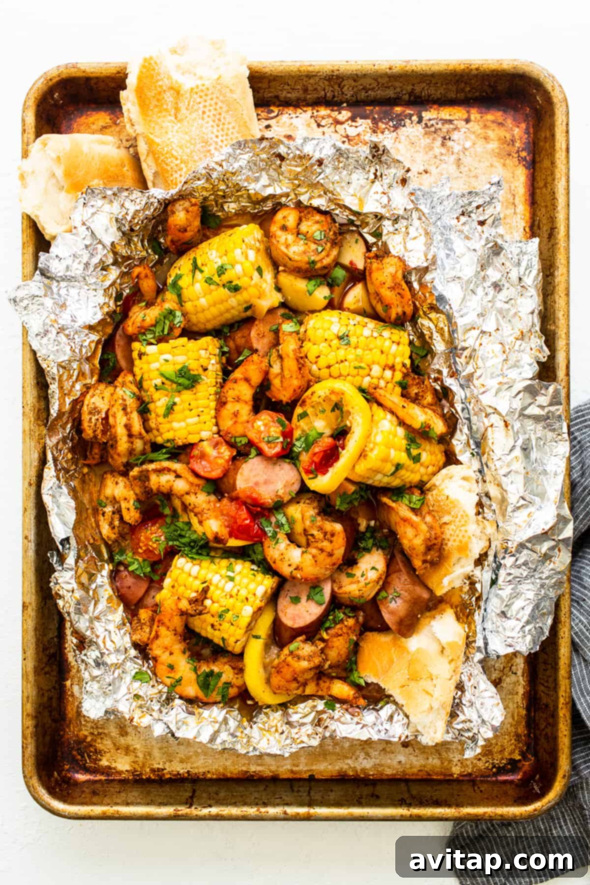 Easy Grilled Shrimp Parcels 2 Shrimp foil packet full of perfectly cooked ingredients, garnished with fresh herbs.