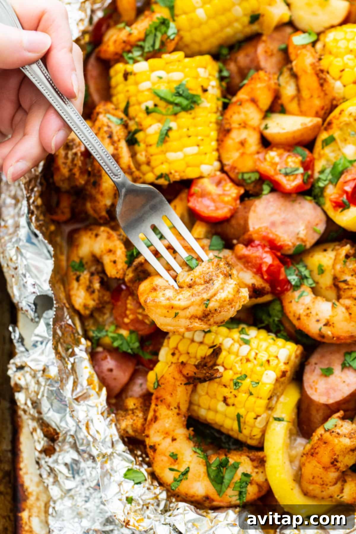 Easy Grilled Shrimp Parcels 7 A fork holding a piece of perfectly cooked shrimp and a potato, highlighting the deliciousness of the foil packets.