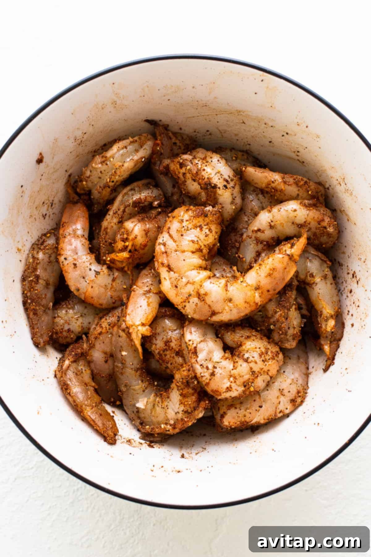 Easy Grilled Shrimp Parcels 5 Close-up of raw jumbo shrimp sitting in a bowl, thoroughly coated in Old Bay seasoning, ready for grilling.