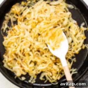 Caramelized onions in a skillet after 30 minutes, beginning to show golden-brown hues.
