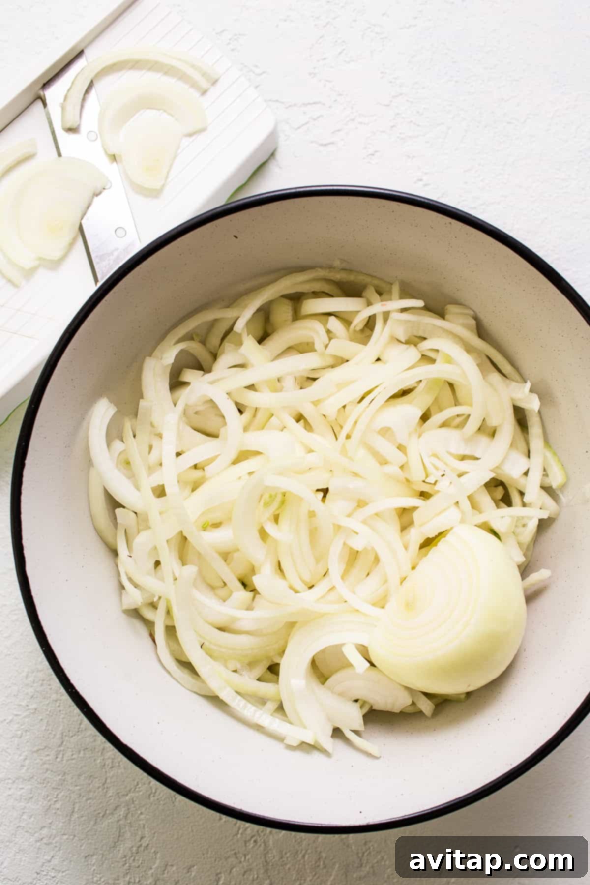 Effortless Golden Caramelized Onions 3 A crisp bowl of freshly sliced white onions, uniformly cut and ready for the caramelization process.