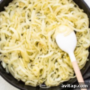 Sliced onions beginning to cook gently in a skillet with olive oil.